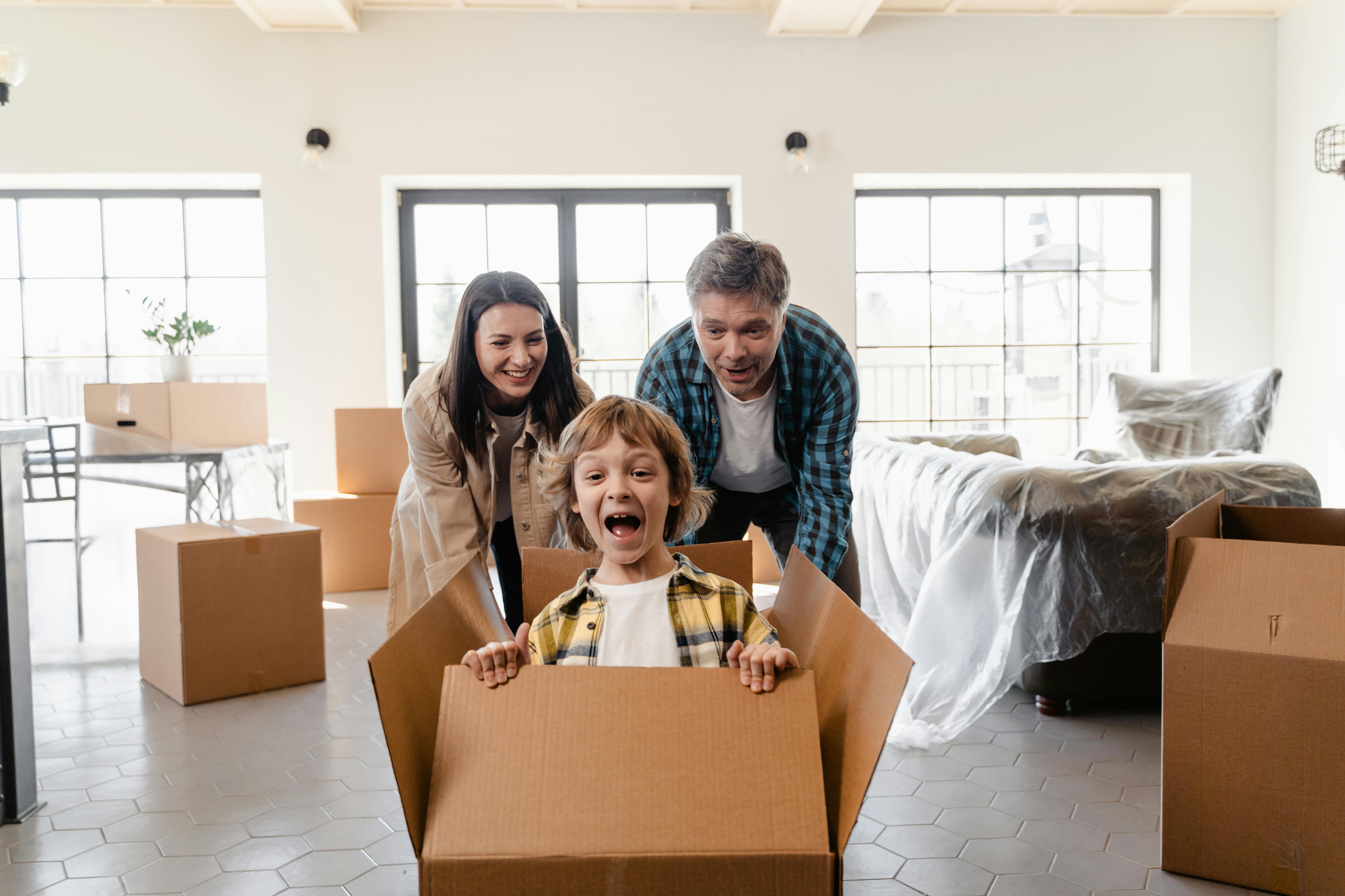 Happy family with child in moving box celebrating their successful move